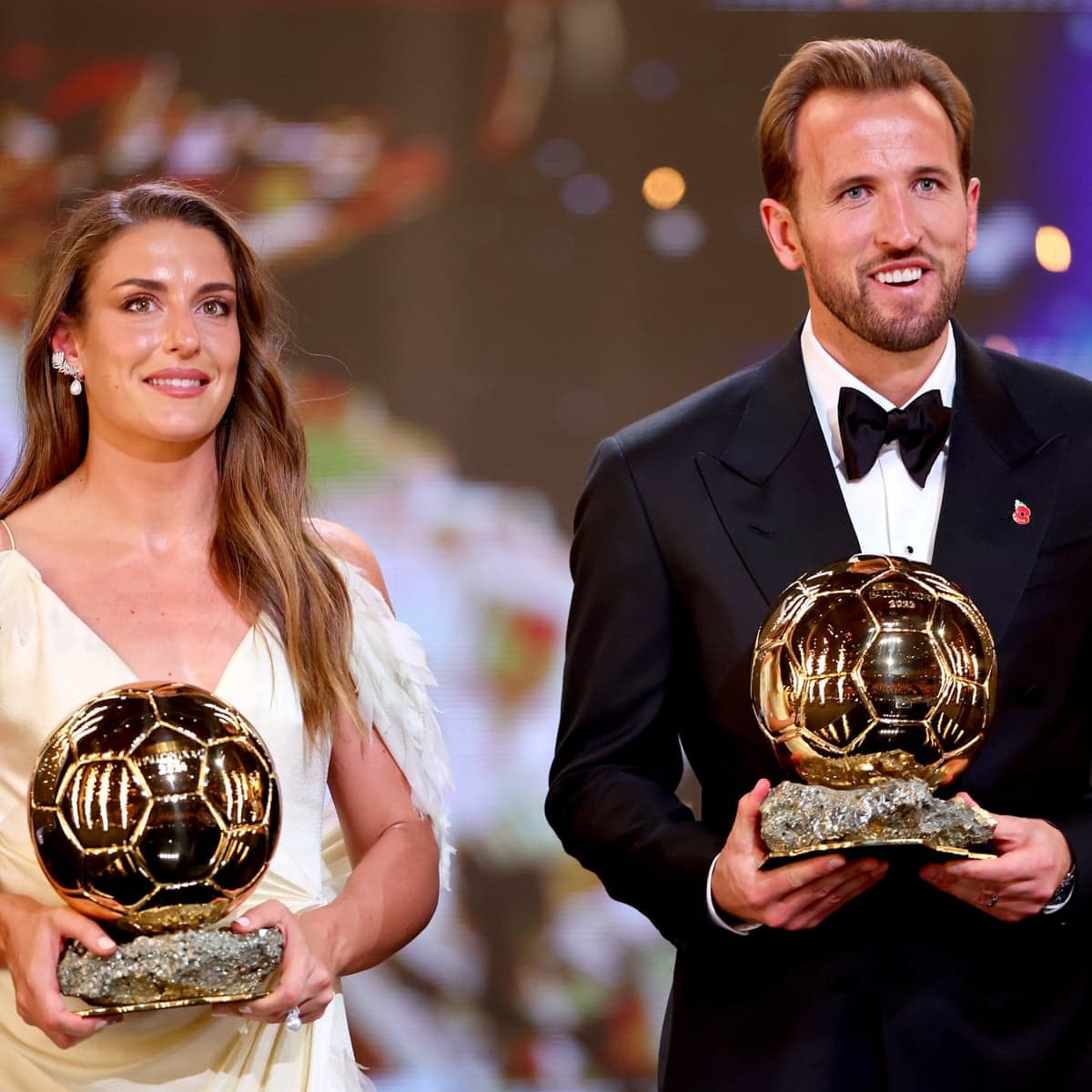 Alexia Putellas and Harry Kane holding their respective Ballon d'Or trophies at the ceremony.