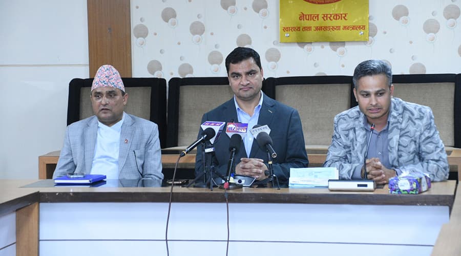 Three men sitting at a table with microphones in front of them, likely at a press conference.