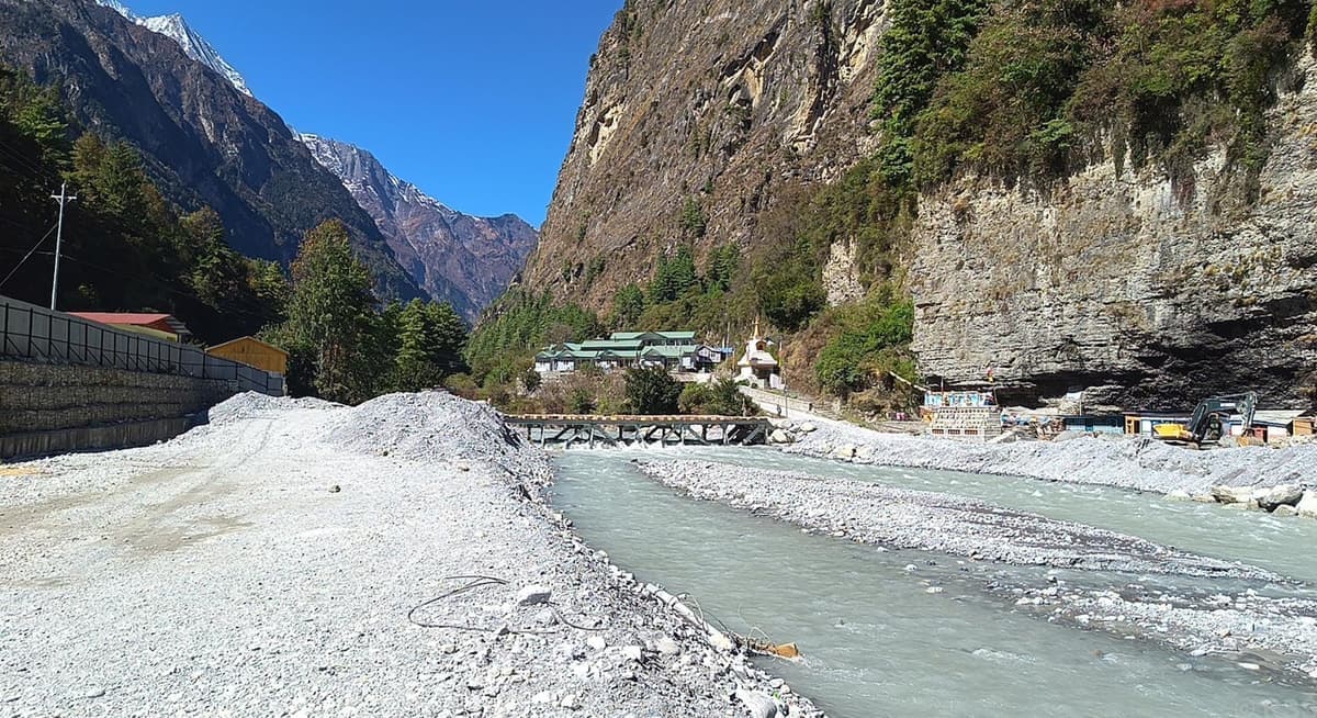 A damaged bridge over a river in a mountainous region.