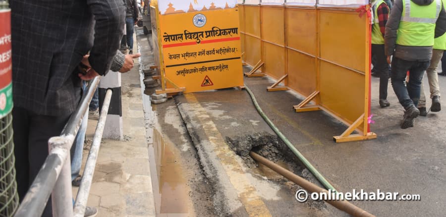 A trench in the road with yellow safety barriers from the Nepal Electricity Authority.