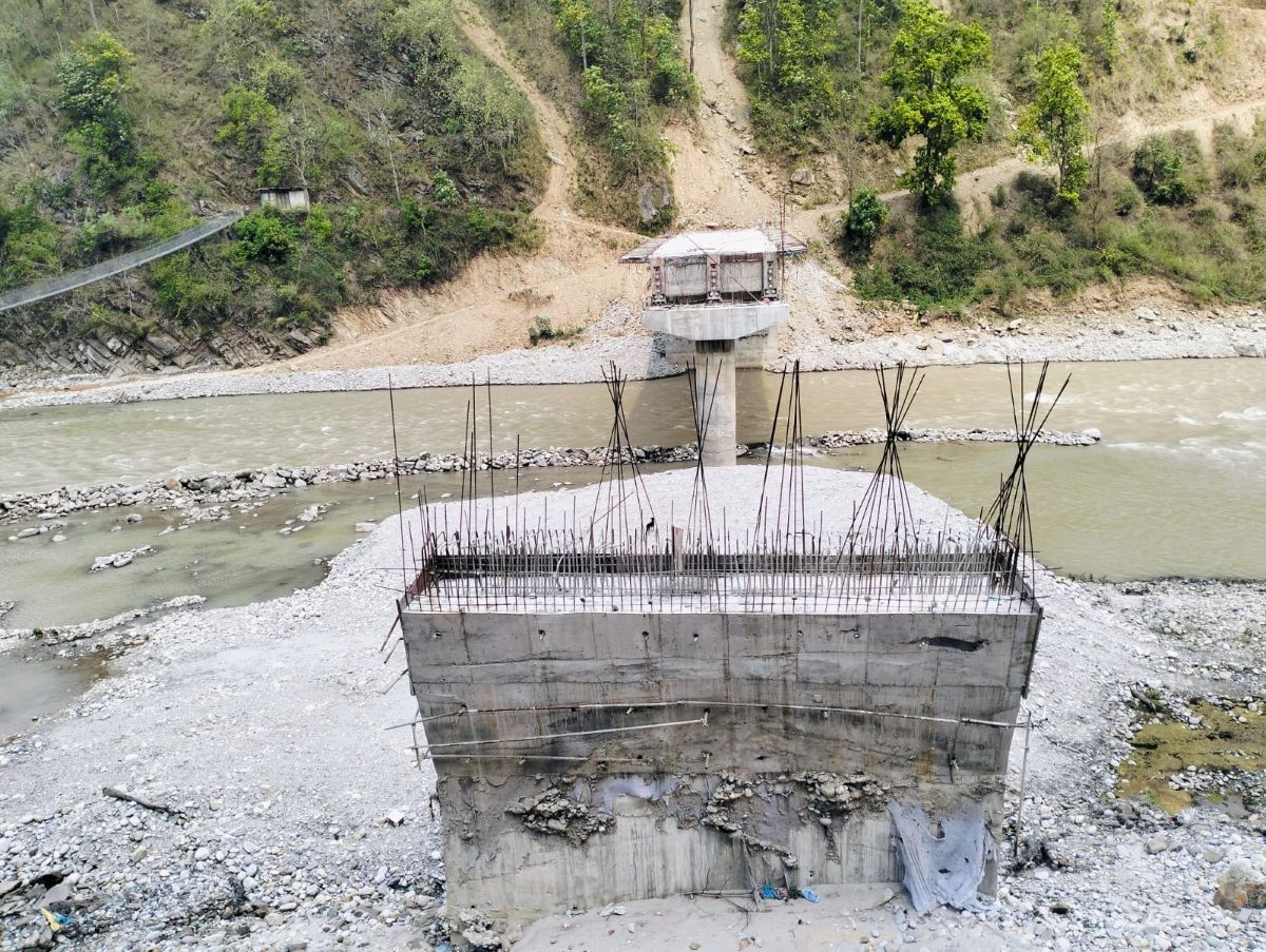 Concrete bridge pillar under construction with exposed rebar standing in a dry riverbed.