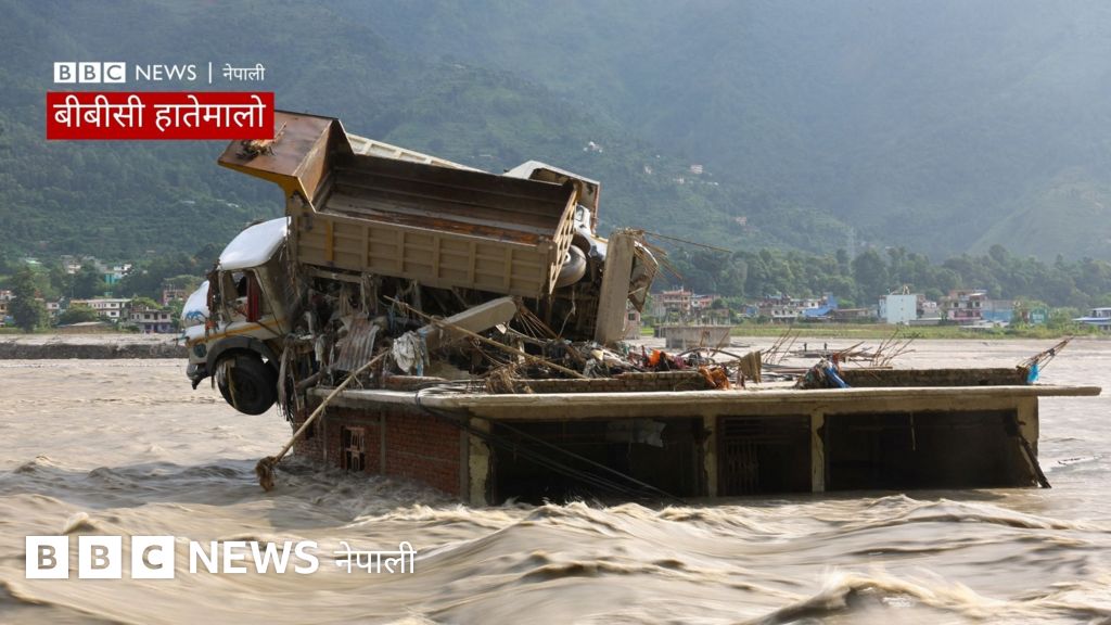 A truck is stuck on top of a partially submerged building in a flooded river.
