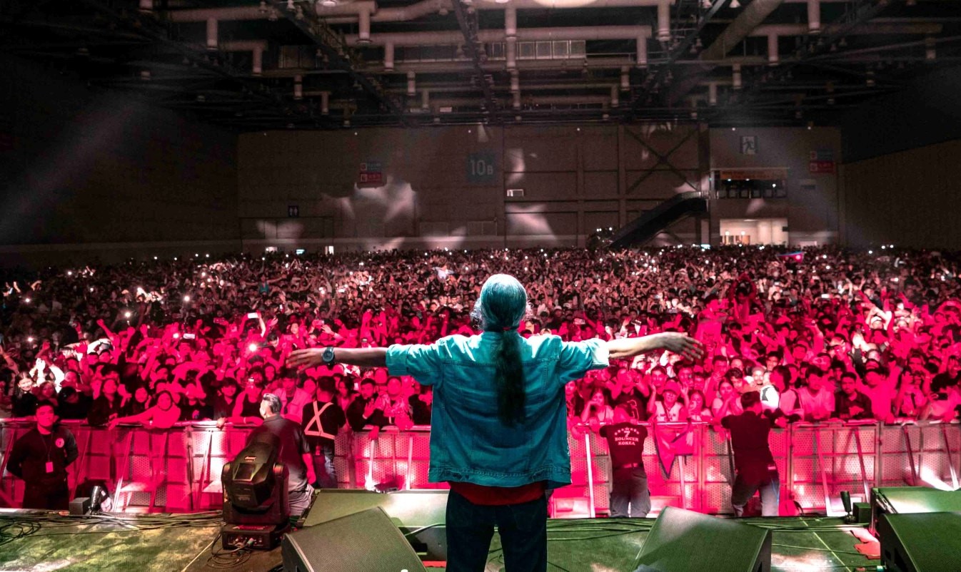 Nepathya lead singer Amrit Gurung opens his arms toward a packed arena audience during a concert.