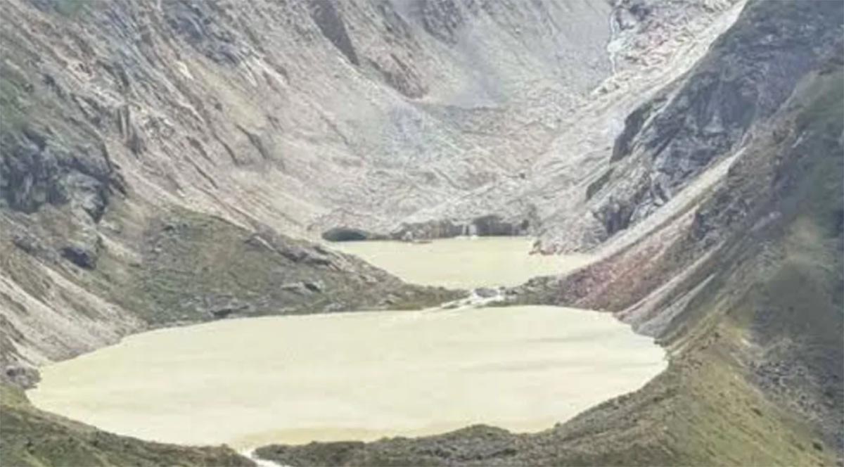 An aerial view of a glacial lake nestled between steep, rocky mountain slopes.