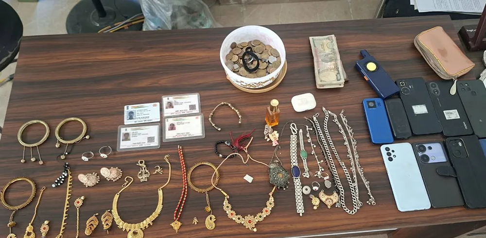 A table covered with recovered stolen goods including jewelry, mobile phones, and identification cards.