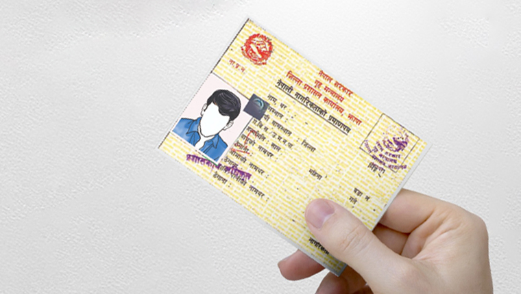 A hand holding a Nepali citizenship certificate.