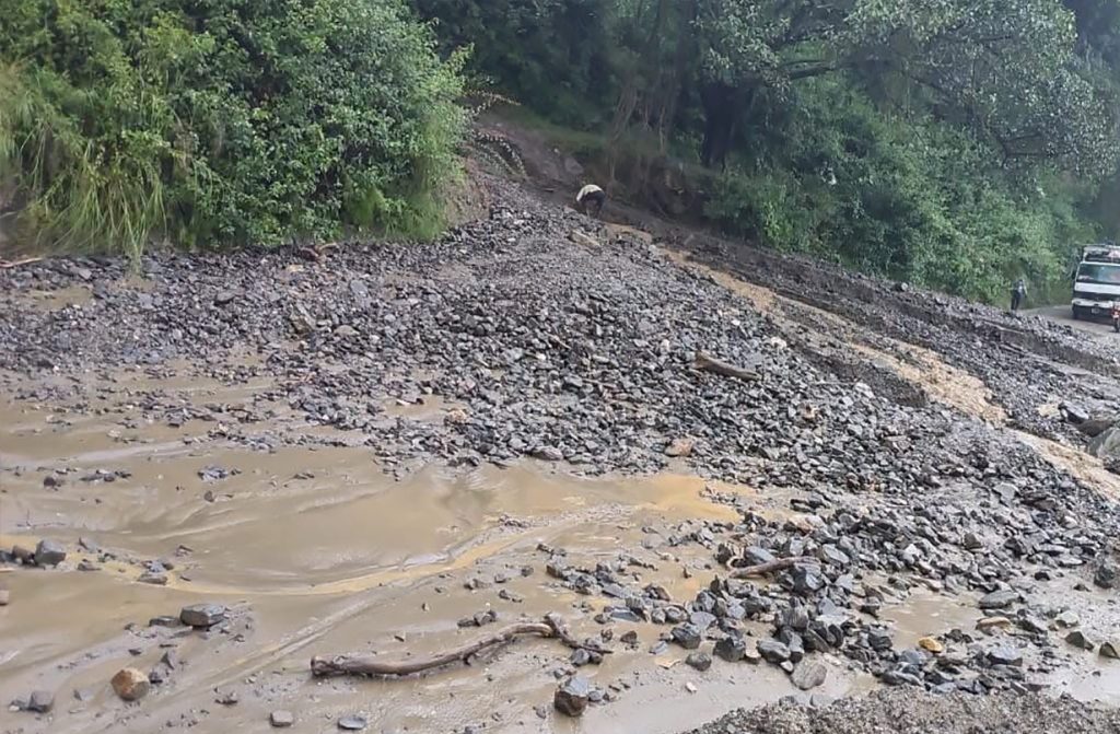 A muddy road blocked by rocks and debris.