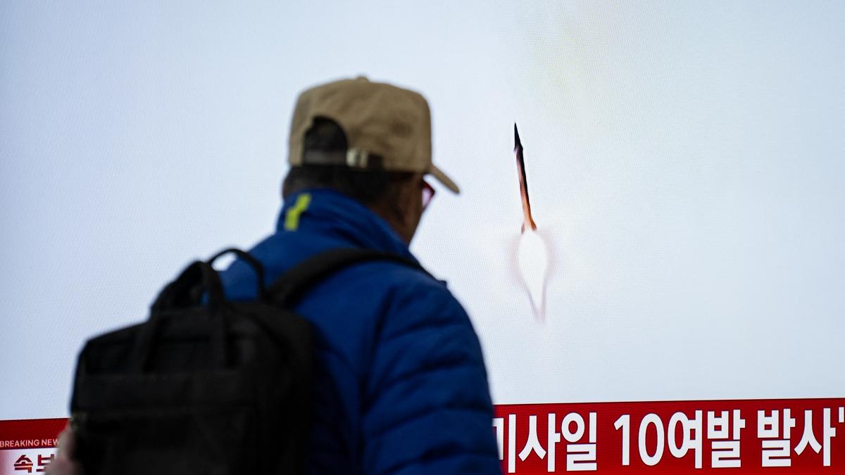 A person watches a news report about a missile launch on a television screen.