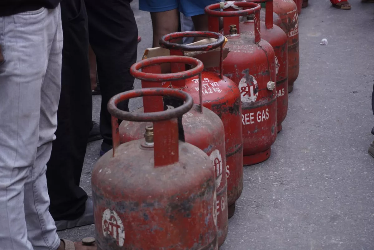 Red cooking gas cylinders lined up in a queue on a street.
