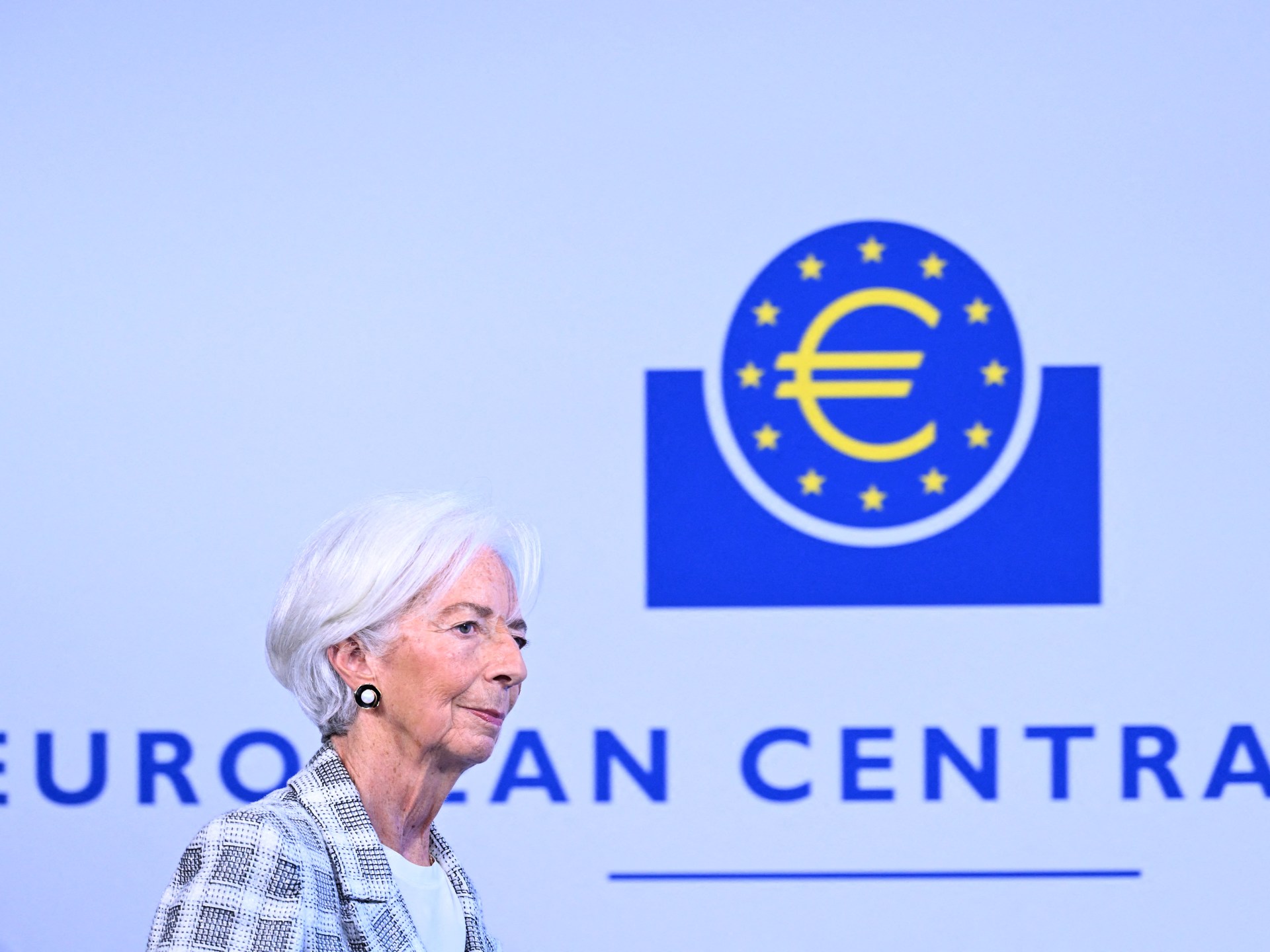 Christine Lagarde walking past a sign that reads European Central Bank.