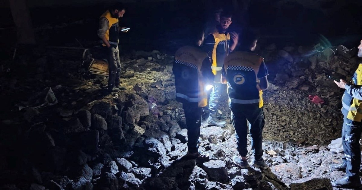 Rescue workers searching through rubble at night.