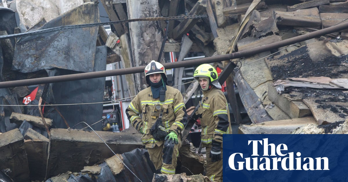 Two firefighters standing in the debris of a destroyed building.